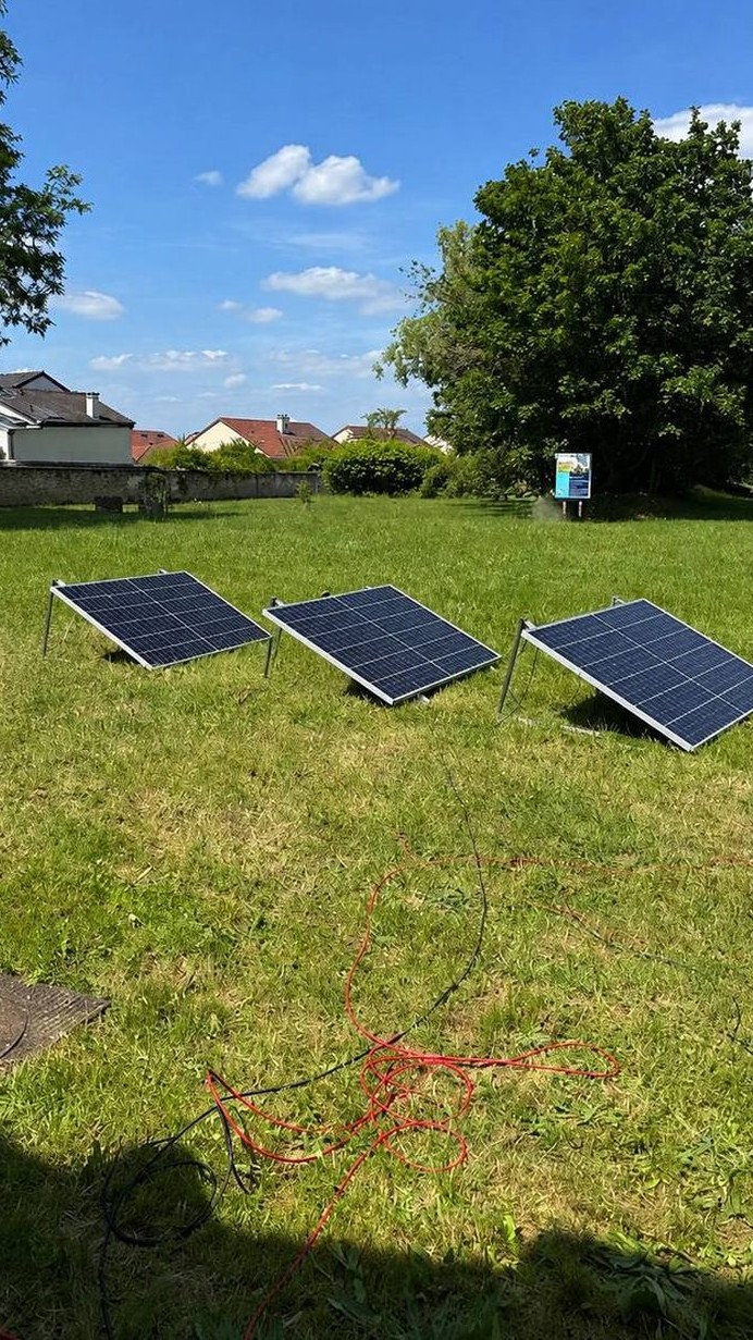 Trois modules photovoltaïques posés sur supports inclinables dans un jardin, orientés plein sud.